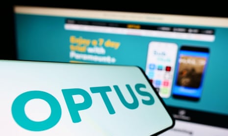 Smartphone with logo of Optus on screen in front of the Optus website on a computer screen