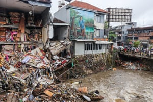 Debris from a collapsed building on the sheer bank of a river in an urban area