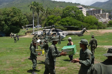 A line of soldiers passing boxes to each other, with a helicopter and trees visible in the background.