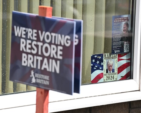 A 'We're Voting Restore Britain' sign on a pole in front of a window with a Trump 2024 poster in Ashton-in-Makerfield