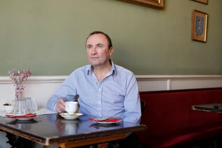 A man sits in a cafe with a cup of tea