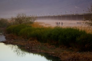 Migrants walk near the border wall after crossing the Rio Bravo with the intention of turning themselves in to the US border patrol agents, as seen from Ciudad Juarez, Mexico