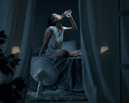 Young woman suffering from insomnia and heat, she is sitting on the bed and drinking water.