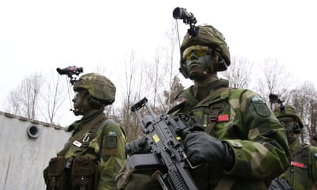 Khaki-clad Swedish Life Guards with faces painted green and holding guns, training near Stockholm