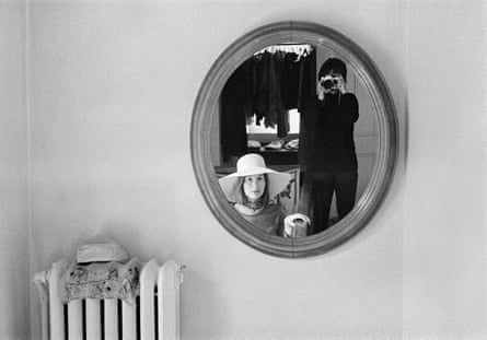 Evelyn Hofer and another woman reflected in a round mirror on a wall next to an iron radiator