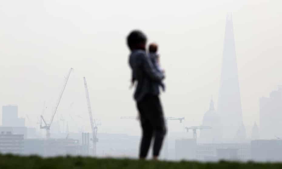 A woman and a child stand on Parliament Hill in Hampstead Heath overlooking a smoggy central London in April 2015.