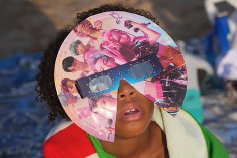 A beachgoer wearing special eclipse glasses looks up during the beginning phase of a solar eclipse at Puerto de Sagunto beach near Valencia, Spain