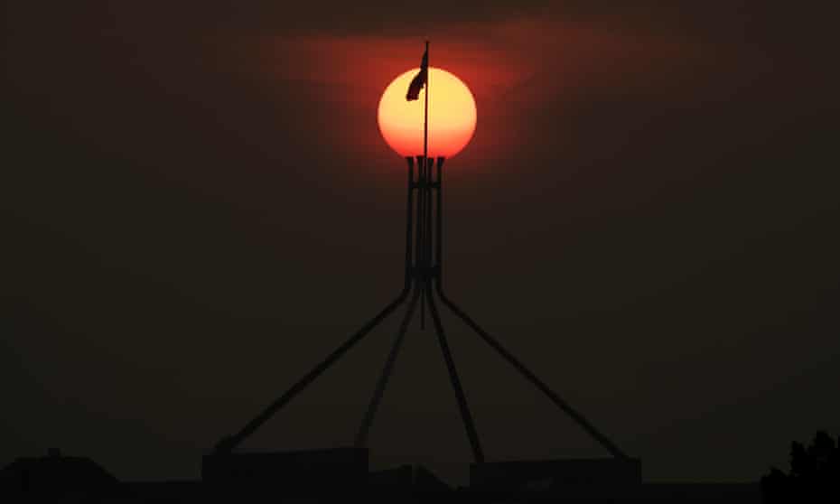 The sun sets through the bushfire smoke haze over Parliament House in Canberra
