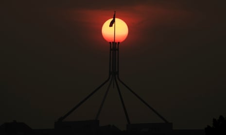 The sun sets through the bushfire smoke haze over Parliament House in Canberra 