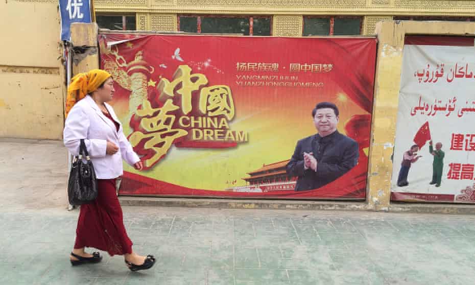 A Muslim Uighur woman in Xinjiang passes a propaganda poster celebrating the ‘China Dream’ of president Xi Jinping.