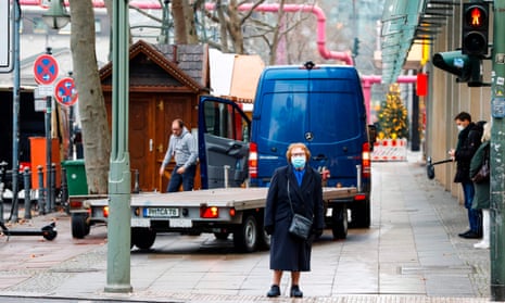 A woman waits at a traffic light as the Christmas market is being dismantled in the background on the Tauentzienstrasse, a major shopping street in the City West Charlottenburg area of Berlin