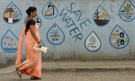 A pedestrian walks past a wall adorned with water conservation messages in Mumbai.