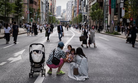 Parents take a picture of their children on a car-free road just as lock-down ended in Tokyo, Japan.  