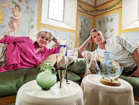 Dan Snow and Dr Kate Lister reclining in a Roman-style room with artifacts
