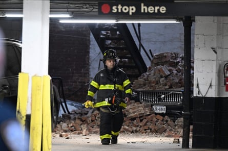Firefighter walks by car covered in rubble