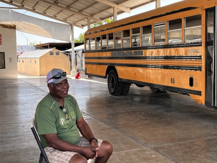 a man sits on a chair near a yellow school bus