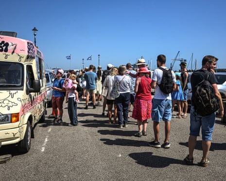 Members of the public queue for solar eclipse glasses at a stall on Custom House Quay in Falmouth, England.