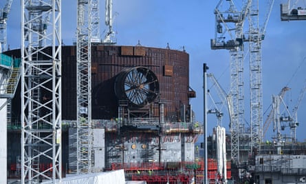 A half completed large cylindrical structure, part of a nuclear reactor, surrounded by cranes 