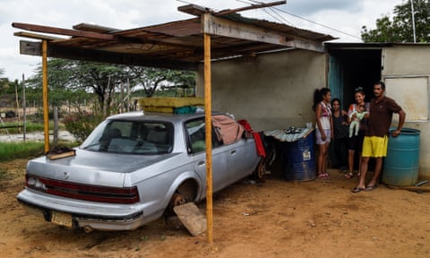 A family stands next to their car out of use due to the lack of spare parts in Maracaibo, Venezuela.