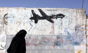 A woman walks past a graffiti depicting a US drone in Sana’a, Yemen. US drone strikes have been used in countries such as Yemen and Somalia, designated by the US as areas of ‘active hostilities’.