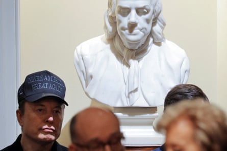 Elon Musk in front of a bust of Benjamin Franklin