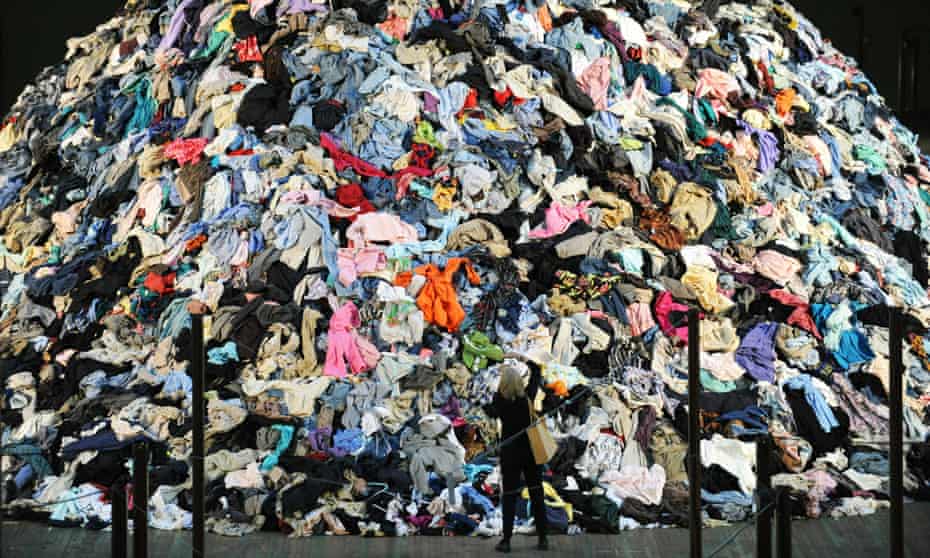 Woman standing by giant pile of clothes