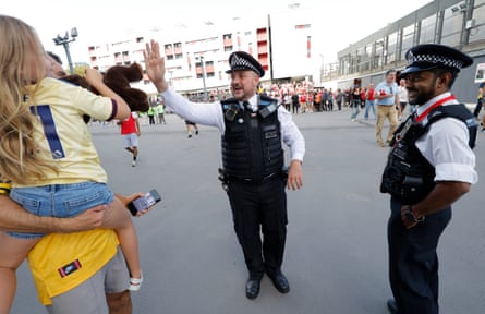 A constable high-fives a young Arsenal fan as he patrols the podium level before kick-off at the Emirates.