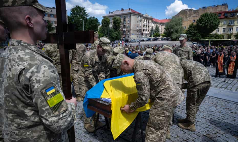 Coffins are draped with Ukrainian flags at a ceremony in Lviv