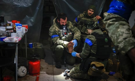 Ukrainian service personnel give first aid to a wounded soldier in a shelter in Soledar.
