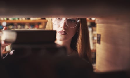 A young woman takes a book from a shelf.