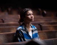 A young woman sits in church pews and looks up