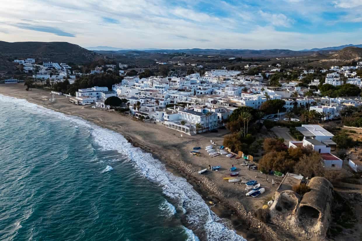 An aerial view of a small seaside resort with white buildings and a long beach