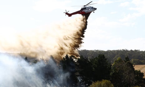 A helicopter dropping sand on a burning forest in Victoria, Australia.