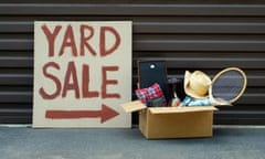 A yard sale sign with a box of sale items at a residential home.