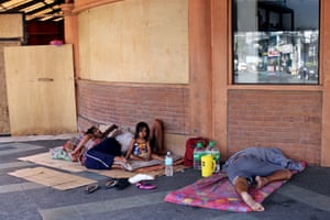 A homeless family rest on the street, in front of a restaurant closed because of COVID-19 lockdown.