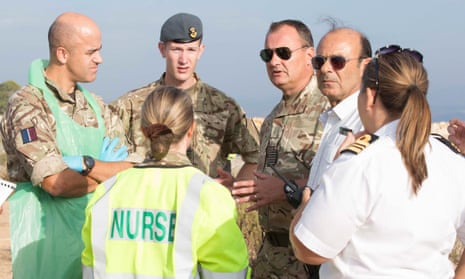 British troops, medics and coastal guard officials discuss the arrival of refugees and migrants at RAF Akrotiri