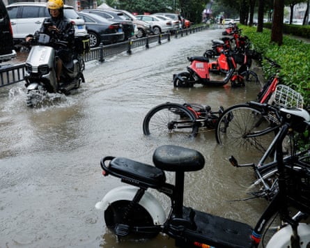 A person rides an electric bike through a flooded street