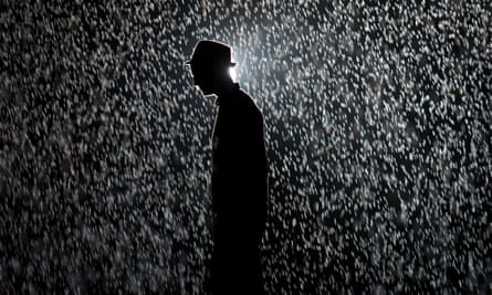 A man poses for pictures as he walks through Rain Room, an installation at the Barbican in London, in 2012.