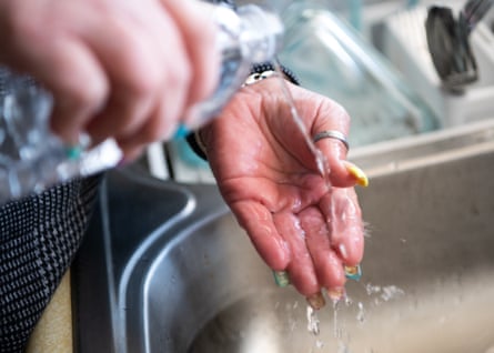 Diana Giffin uses bottled water to clean her hand after cutting up an avocado at her home.