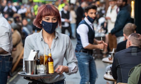 Waiters serve people eating and drinking at outside tables in Soho, central London