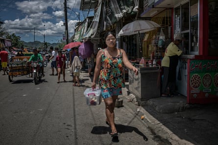 Rhoda, a widow who is raising seven children after her husband was killed in an extrajudicial killing, walks through the streets of Payatas to deliver a sale of an Avon product, which she started selling door to door in January 2018.