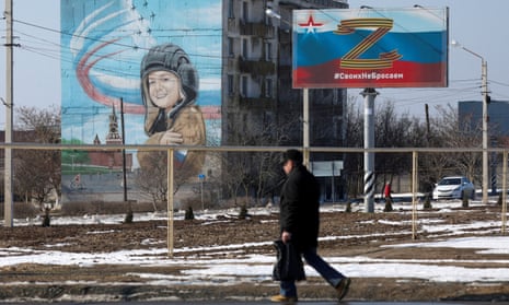 A man walks past a billboard displaying the ‘Z’ symbol in support of Russian armed forces in Chernomorskoye, Crimea.