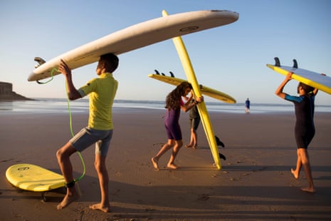 Boys and a girl carrying surf boards