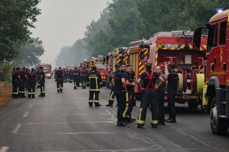 Dozens of firefighters stood next to fire engines lining a street.