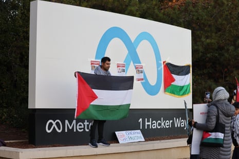 Protesters unfurl the Palestinian flag in front of a sign with the Meta name, symbol and address.