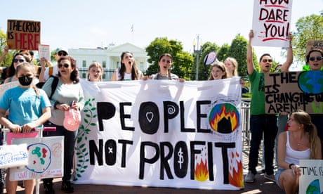 People hold a large sign proclaiming 'People not profit'