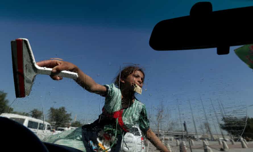 An Iraqi girl cleans the windscreen of a car at traffic lights in the capital.
