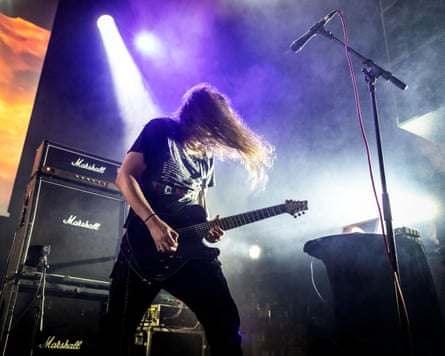 Broadrick playing guitar live on stage under a purple spotlight