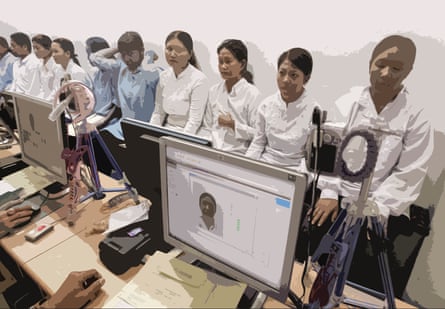 A row of women standing in front of desks with computers and cameras