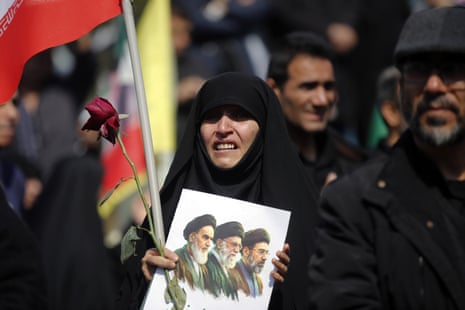A woman holds an image of Iranian leaders killed in the war.